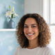 A smiling young woman in her late 20s looking at the camera, conveying trust and satisfaction.